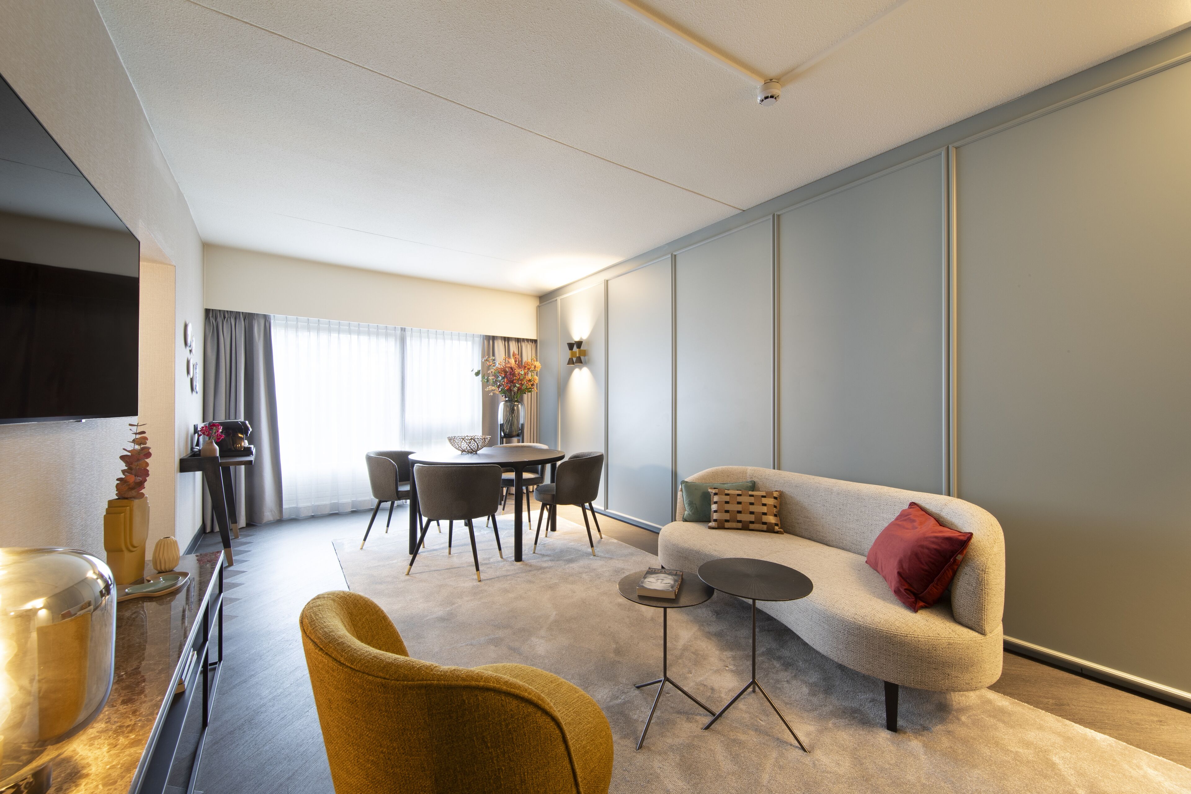 A modern living room with a sofa, armchair, and a small round table.