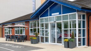 A building with a blue roof, large windows, and outdoor seating with umbrellas. - Holiday Inn Express Burton Upon Trent by IHG (Burton on Trent)