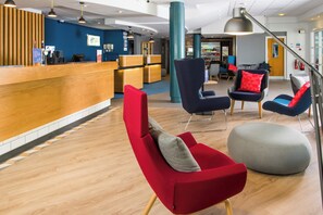 A modern hotel lobby with a reception desk, seating area, and a staircase. - Holiday Inn Express Burton Upon Trent by IHG (Burton on Trent)