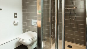 A modern bathroom with a toilet, a glass-enclosed shower, and grey tiled walls. - Holiday Inn Express Burton Upon Trent by IHG (Burton on Trent)