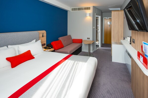 Une chambre d’hôtel avec un grand lit, un canapé, un bureau et une télévision.