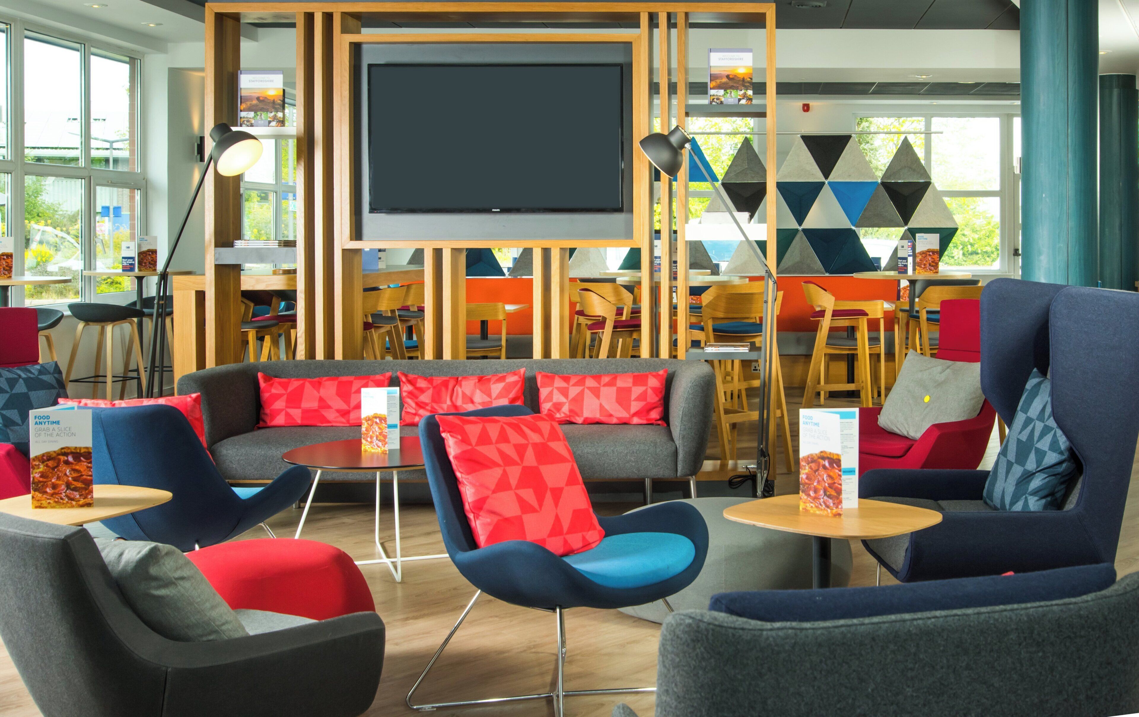 Ein stilvoller Lounge-Bereich mit Sofas, Sesseln und einem großen Bildschirm.