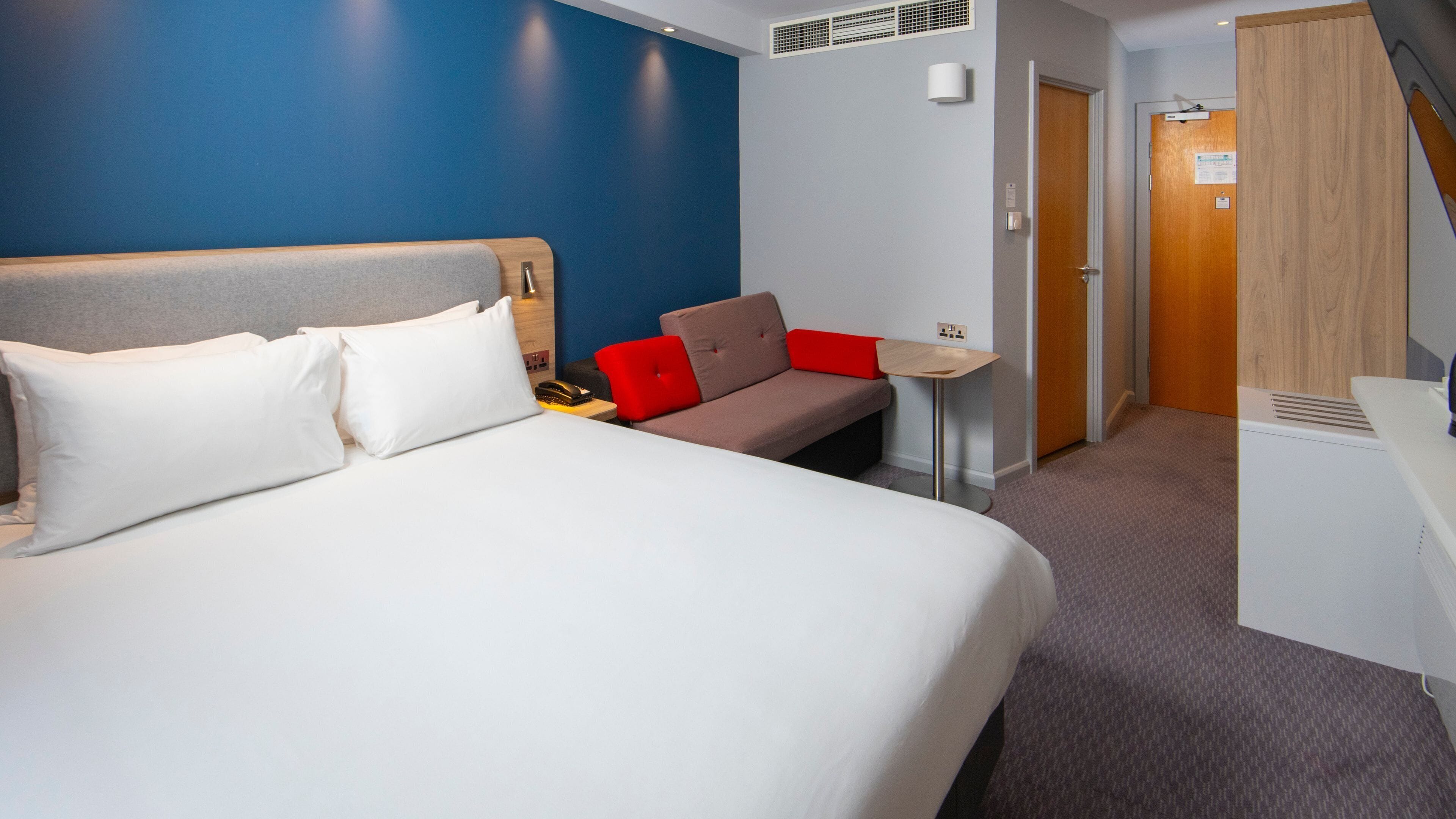 Une chambre d’hôtel avec un grand lit, un canapé, une petite table et un bureau.