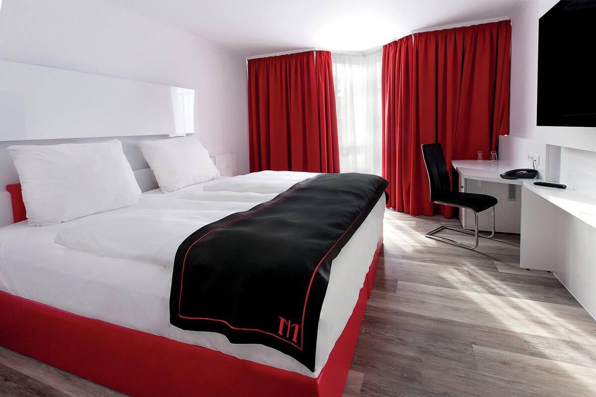 Une chambre d’hôtel avec un grand lit, un bureau avec une chaise et un téléviseur.