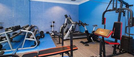 A gym with various exercise equipment, including a treadmill, weight bench, and dumbbells.