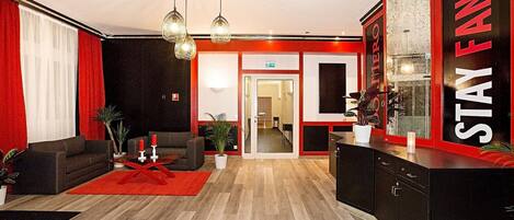 Un vestíbulo de hotel con una decoración en rojo y negro, una mesa de recepción y un área de estar con un tapete rojo.