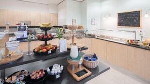 A breakfast buffet with various fruits, a milk dispenser, and a chalkboard with a message. - Best Western Hotel Im Forum Muelheim (Muelheim an der Ruhr)