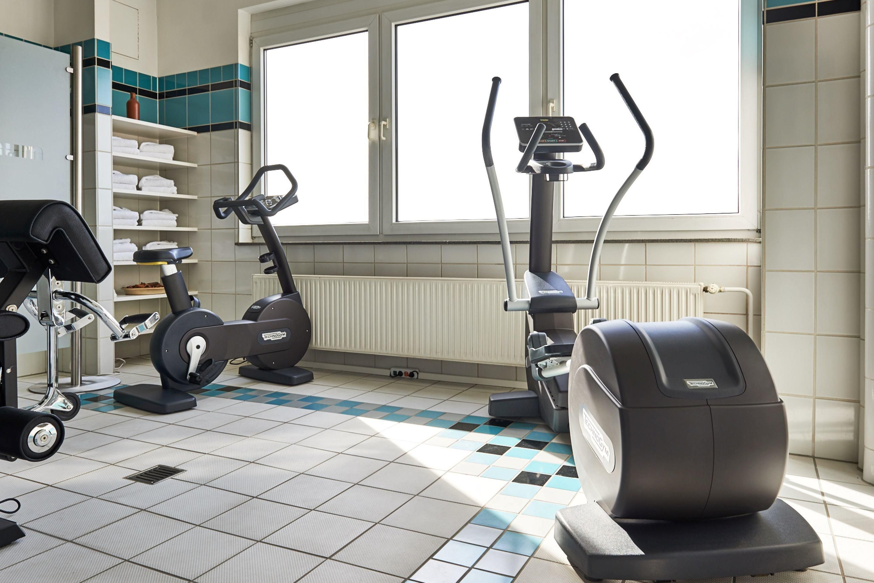 A gym with exercise equipment, a window, and a tiled floor.