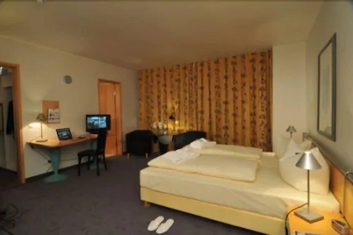 A hotel room with two beds, a desk with a computer, a chair, and a TV.