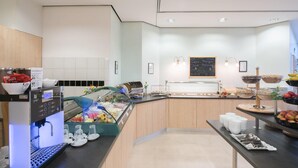 A modern breakfast area with a coffee machine, fruit display, and a chalkboard menu. - Best Western Hotel Im Forum Muelheim (Muelheim an der Ruhr)