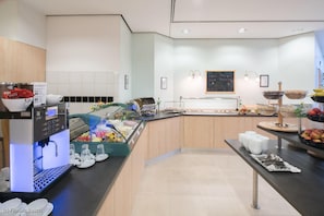A modern breakfast area with a coffee machine, fruit display, and a chalkboard menu. - Best Western Hotel Im Forum Muelheim (Muelheim an der Ruhr)