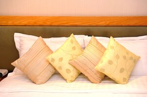 Una cama con cabecera de madera y cuatro almohadas con motivos de hojas.