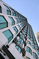 Un edificio de gran altura con un diseño arquitectónico moderno, que presenta una serie de balcones y ventanas amplias.