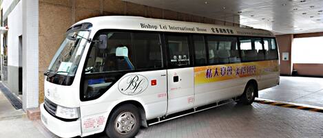 Un autobús blanco con la leyenda 'Bishop Lei International House' estacionado dentro de un edificio.