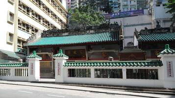 A traditional Chinese building with a green roof and white walls, featuring a gate and a statue.