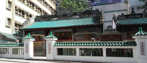 A traditional Chinese building with a green roof and white walls, featuring a gate and a statue.