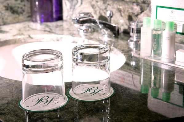 Two glass jars with lids on a granite countertop in a bathroom.