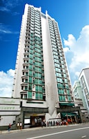 A tall, modern hotel with a prominent entrance and a large number of windows.