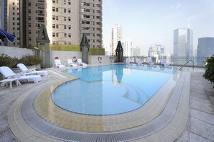 Piscina en la azotea con sillones de descanso y vista panorámica de la ciudad.