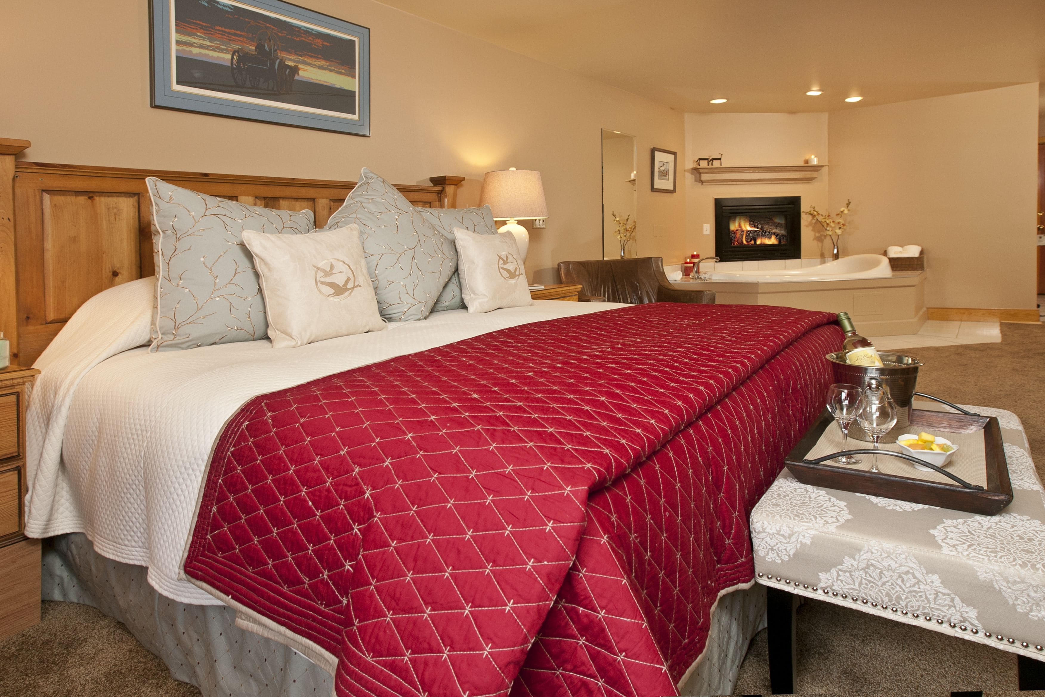 A hotel room with a large bed, a sitting area with a fireplace, and a tray with breakfast items.