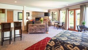 A hotel room with a large bed, a dining area, a kitchen, and a view of the outdoors. - Inn on the Creek (Jackson)