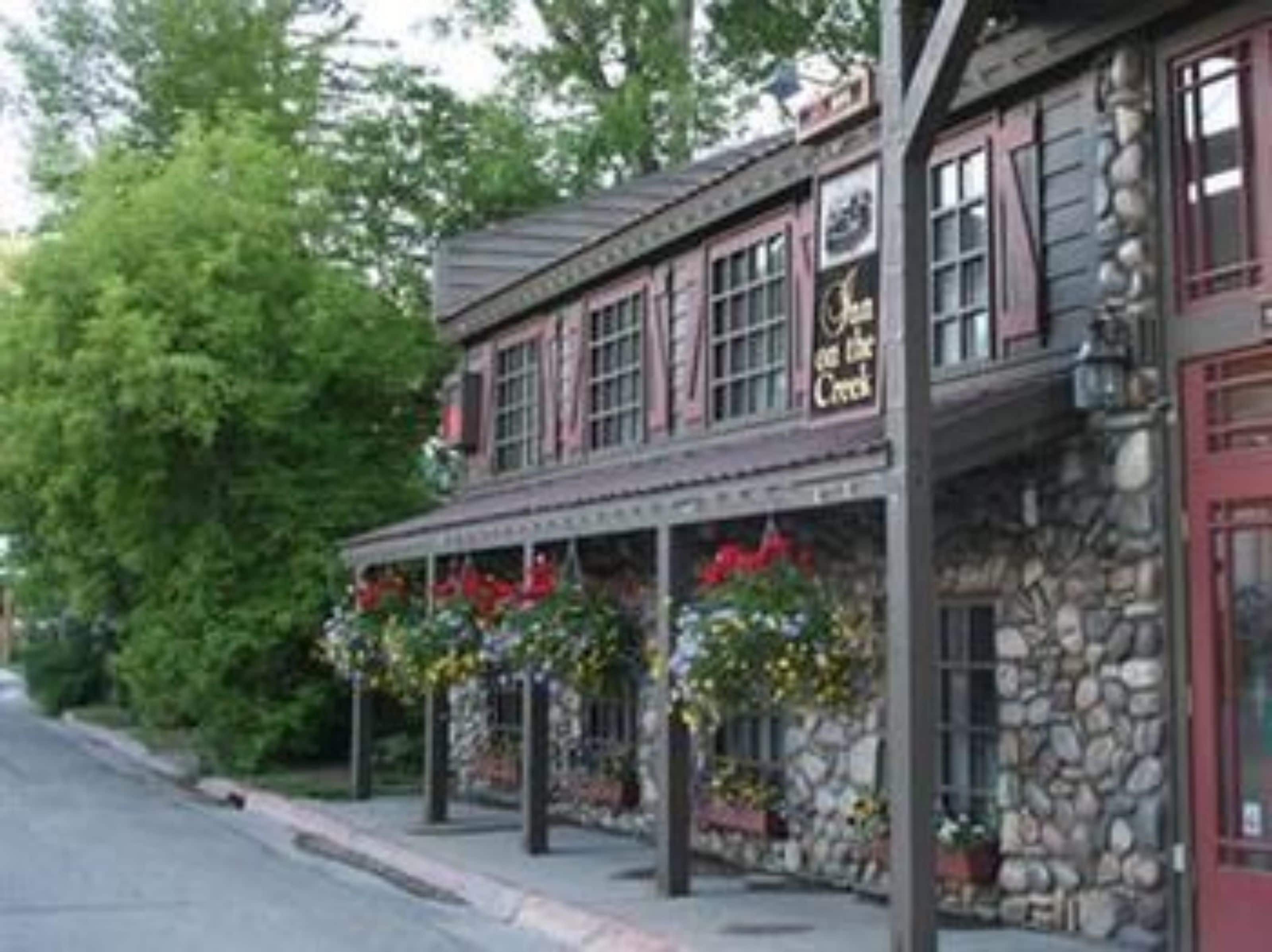 A stone building with a red door and windows, labeled "The Inn at the Creek."