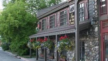 A stone building with a red door and windows, labeled "The Inn at the Creek."