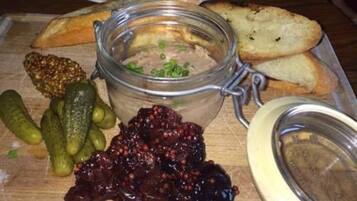 A wooden table with a glass jar of spread, pickles, and bread.