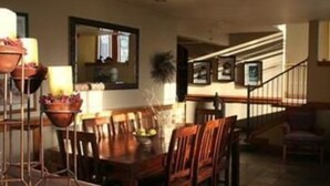 A dining area with a wooden table and chairs, a potted plant, and a staircase leading to another level. - Inn on the Creek (Jackson)