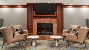 A lobby with a fireplace, two armchairs, and two small tables.