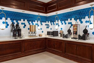 A modern kitchen with a white countertop, wooden cabinets, and a blue hexagonal tile backsplash.