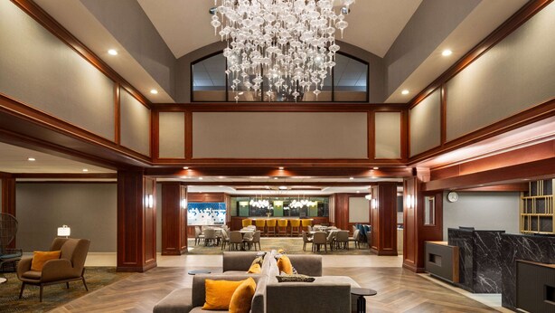 A spacious lobby with a high ceiling, a large chandelier, and a reception desk.