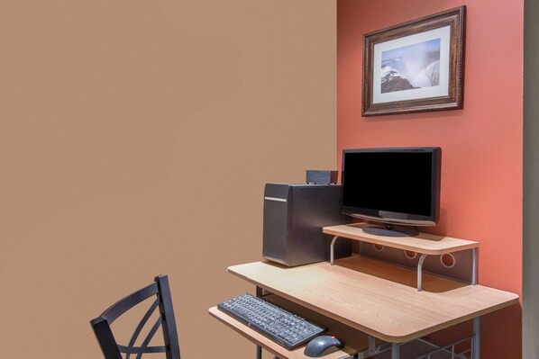 A computer desk with a monitor, keyboard, and mouse.