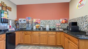 A kitchen with wooden cabinets, a coffee machine, and a microwave. - Super 8 by Wyndham Youngstown/Austintown (Austintown)