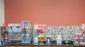 A kitchen counter with coffee machines, a fruit display, and a coffee station.