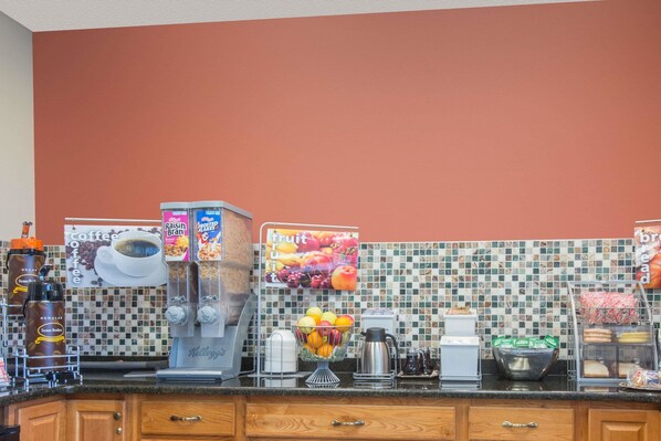 Una encimera de cocina con cafeteras, una exposición de fruta y una estación de café.