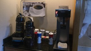 A coffee station with a coffee machine, a water dispenser, and a coffee cup on a counter. - Super 8 by Wyndham Youngstown/Austintown (Austintown)