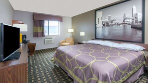 A hotel room with a bed, a TV, a chair, a desk, and a large window with a cityscape view. - Super 8 by Wyndham Youngstown/Austintown (Austintown)