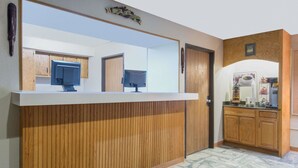 A reception area with a wooden counter, a large mirror, a coffee machine, and wooden cabinets. - Super 8 by Wyndham Youngstown/Austintown (Austintown)