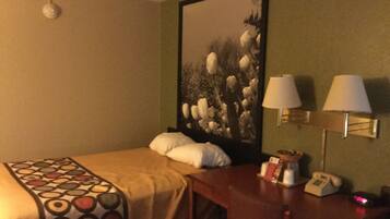 Habitación de hotel con cama, escritorio y teléfono, y una lámpara de pared.