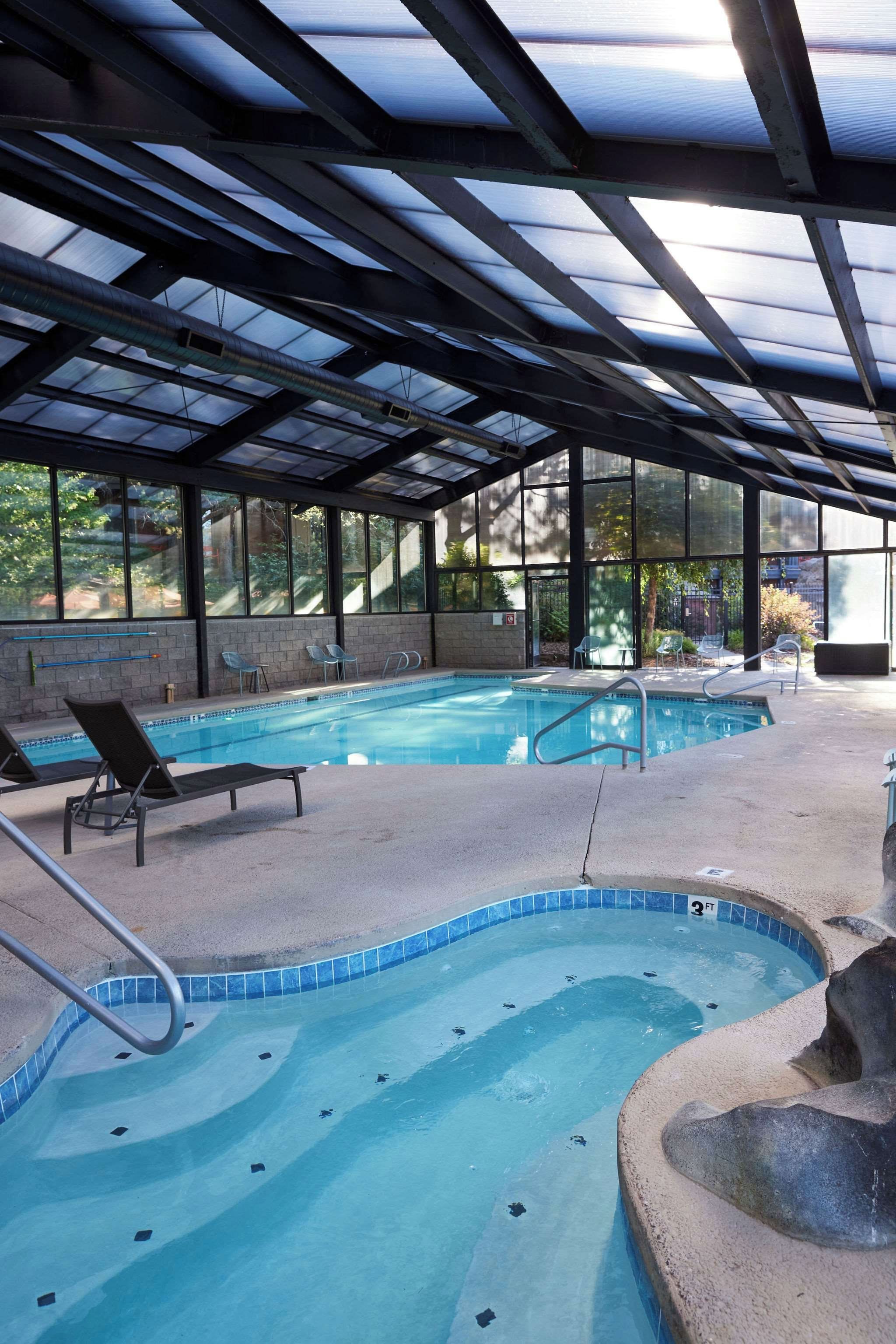 Una piscina exterior techada con sillones reclinables y un jacuzzi.