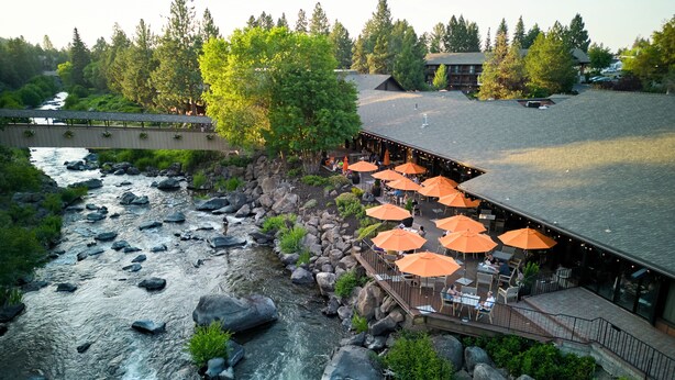 A riverside restaurant with outdoor seating and a view of the river.