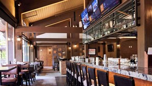 A bar area with a long counter, multiple TVs, and a patterned carpet.