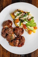 Un plato de comida con huevos, aguacate y carne.