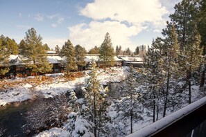 A snowy landscape with a river, trees, and buildings in the background. - Riverhouse Lodge (Bend)