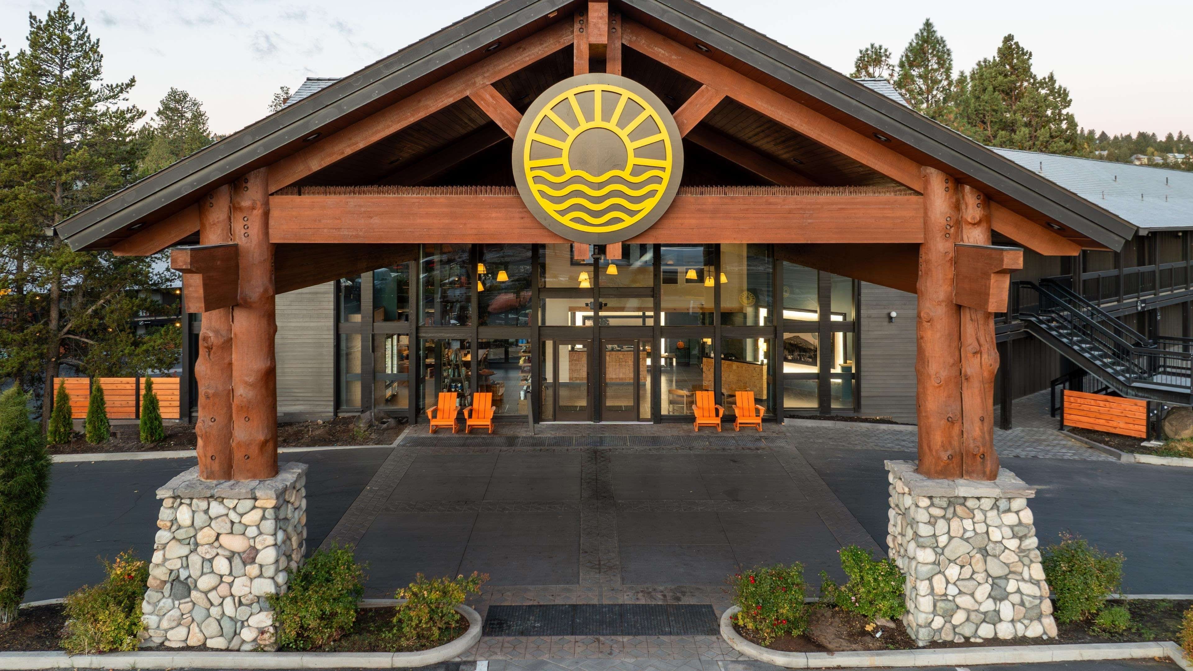 A lodge entrance with a wooden structure, stone pillars, and a sun emblem.