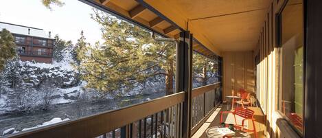A balcony with a view of a snow-covered landscape and a river.