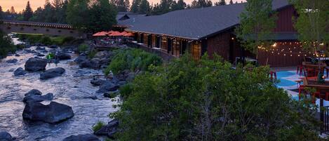 A riverside lodge with outdoor seating and a pool area.