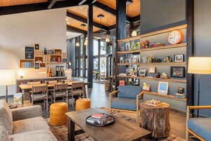 Un espacio lounge acogedor con asientos, una estación de café y estantes con libros y objetos decorativos.