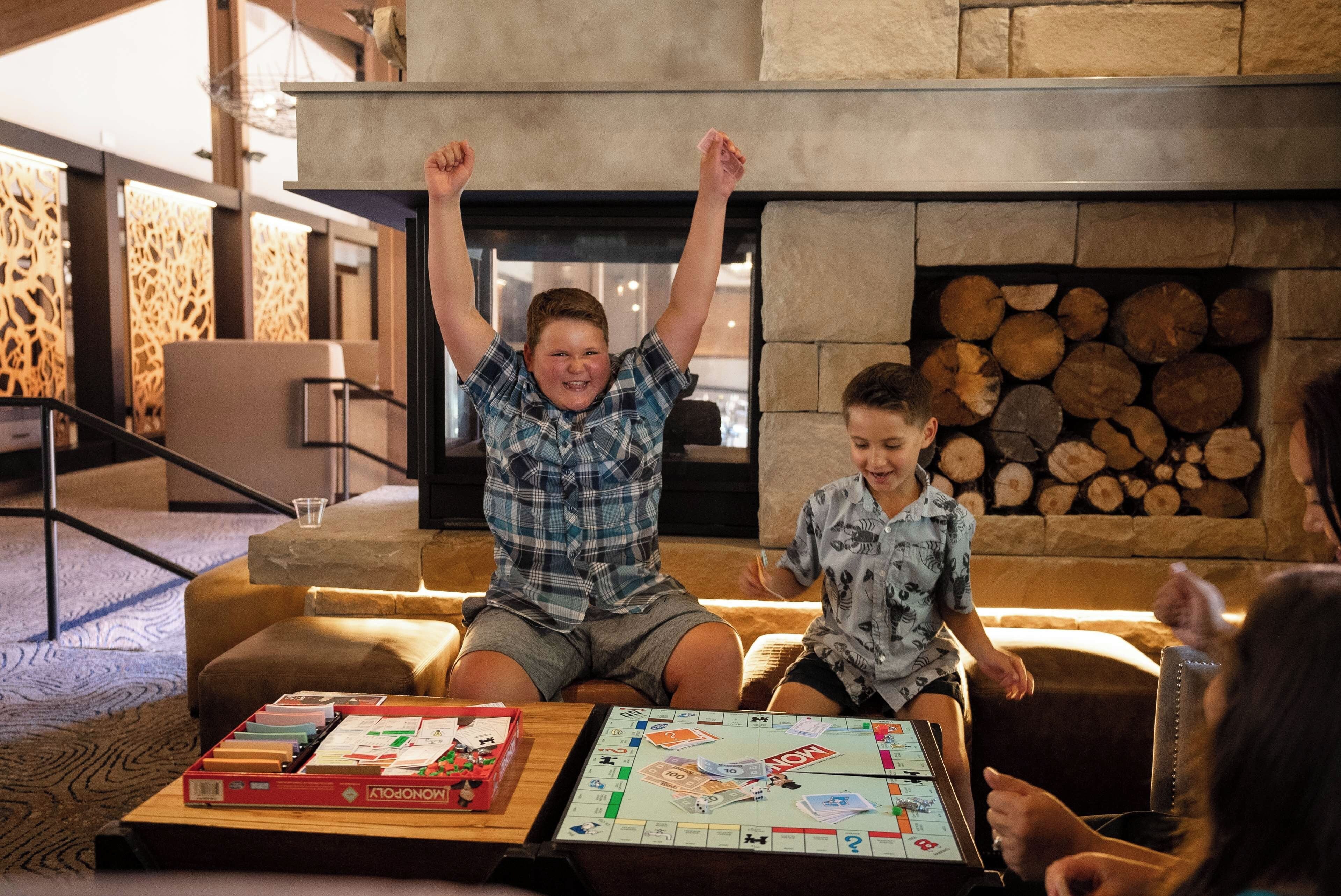A group of people playing a board game in a room with a fireplace and a stone wall.